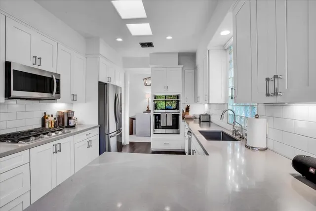 a kitchen with stainless steel appliances a sink a stove a refrigerator cabinets and a counter top space