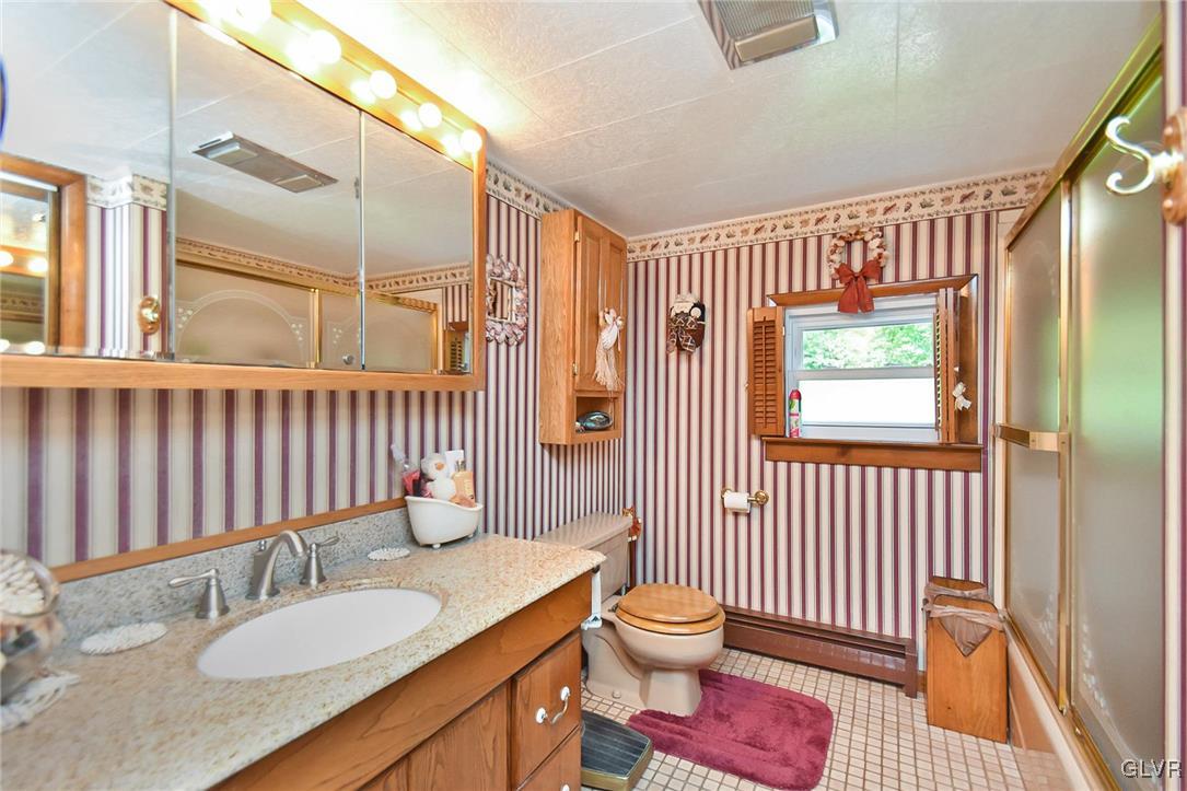 3015 Mountain Road Slatington, PA 18080 - Photo 13 of 32 a bathroom with a granite countertop sink a toilet and a mirror