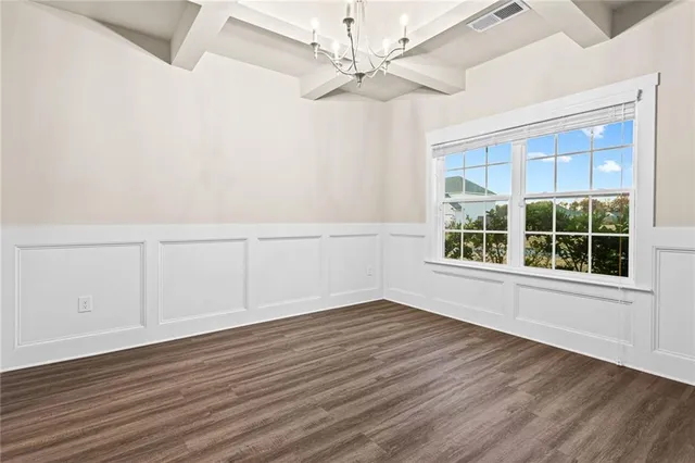 an empty room with wooden floor chandelier fan and windows