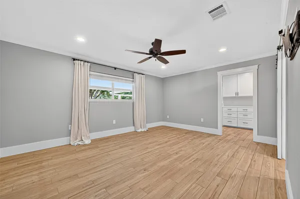 a view of an empty room with a window and wooden floor
