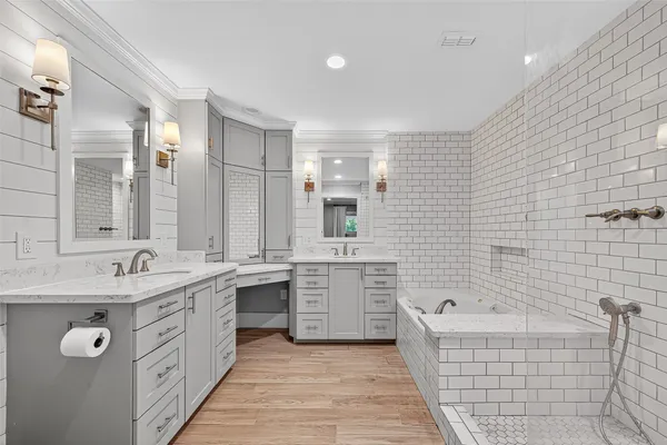 a bathroom with a granite countertop double vanity sink a mirror bathtub and double