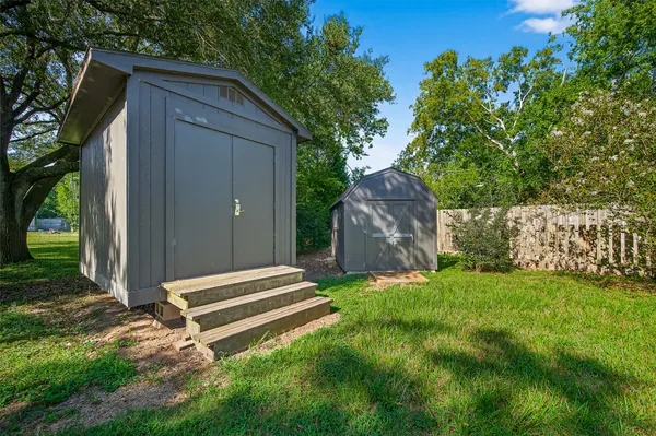 a backyard of a house with a large tree and wooden fence