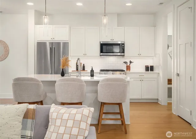 a kitchen with stainless steel appliances granite countertop a sink a microwave a refrigerator and white cabinets