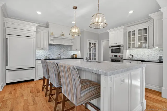 a kitchen with stainless steel appliances granite countertop a stove top oven a refrigerator a sink and dishwasher with wooden floor