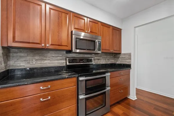 a kitchen with granite countertop wooden cabinets and stainless steel appliances