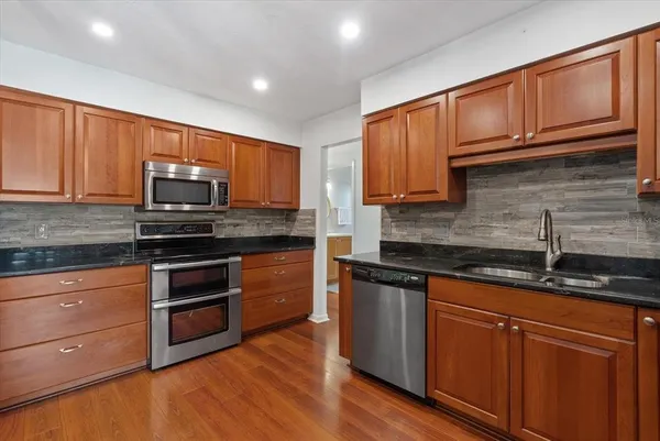 a kitchen with granite countertop wooden cabinets stainless steel appliances and a sink