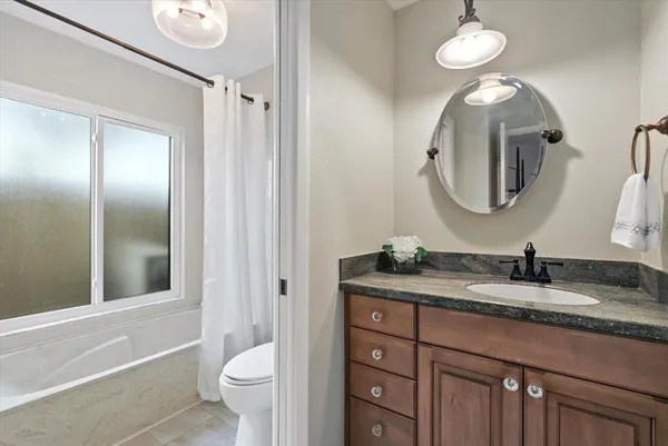 a bathroom with a granite countertop sink toilet and a mirror