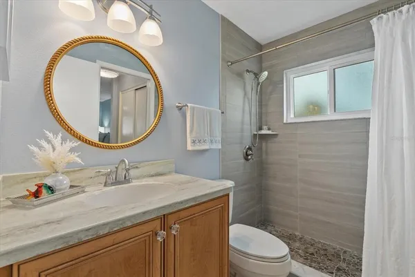 a bathroom with a granite countertop toilet a sink and a mirror