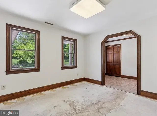 a view of an empty room with window and closet area