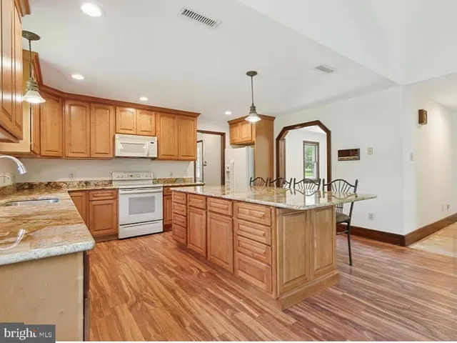 a kitchen with stainless steel appliances granite countertop a stove a sink dishwasher and white cabinets with wooden floor