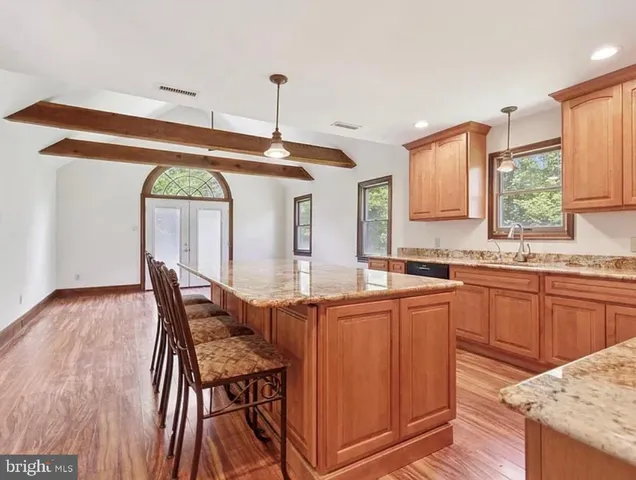 a kitchen with stainless steel appliances granite countertop a kitchen island hardwood floor sink stove dining table and chairs