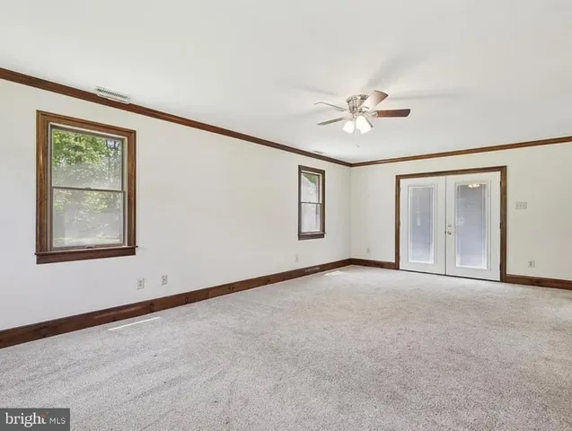 an empty room with chandelier fan and windows