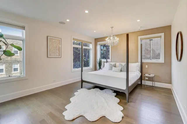 a bedroom with a bed a mirror and a bookshelf with wooden floor
