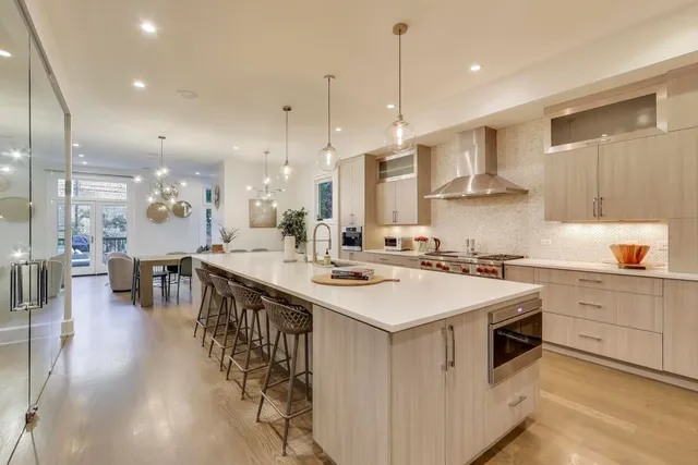 a large white kitchen with a stove a sink a refrigerator and a dining table with wooden floor