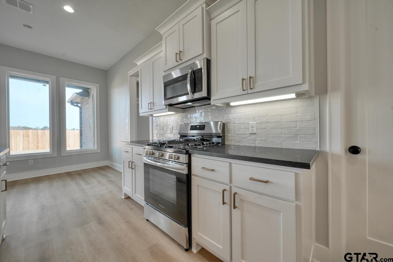 636 Prince Lane Tyler, TX 75704 - Photo 12 of 38 a kitchen with stainless steel appliances granite countertop a stove a sink and a microwave