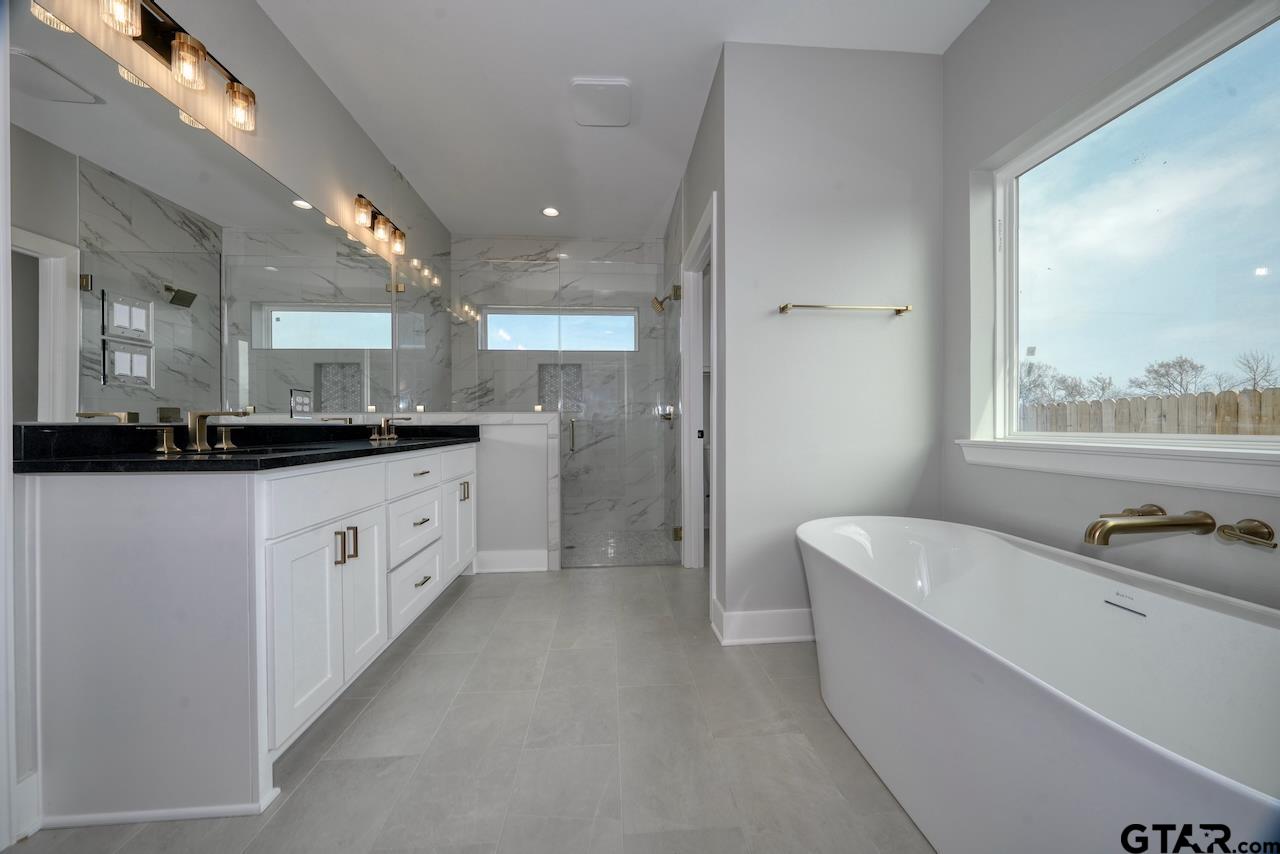 636 Prince Lane Tyler, TX 75704 - Photo 19 of 38 a large white bathroom with a double vanity sink a mirror and a bathtub
