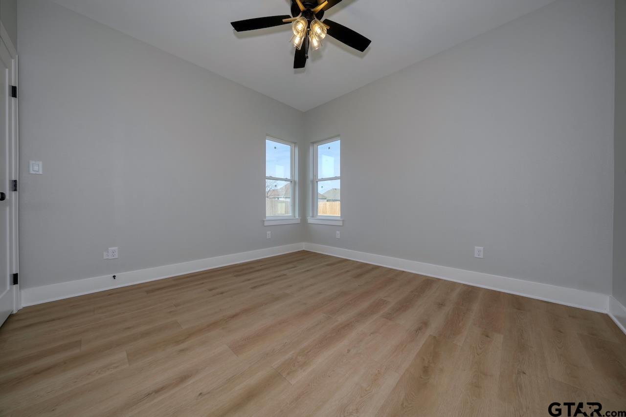 636 Prince Lane Tyler, TX 75704 - Photo 30 of 38 an empty room with wooden floor chandelier fan and windows