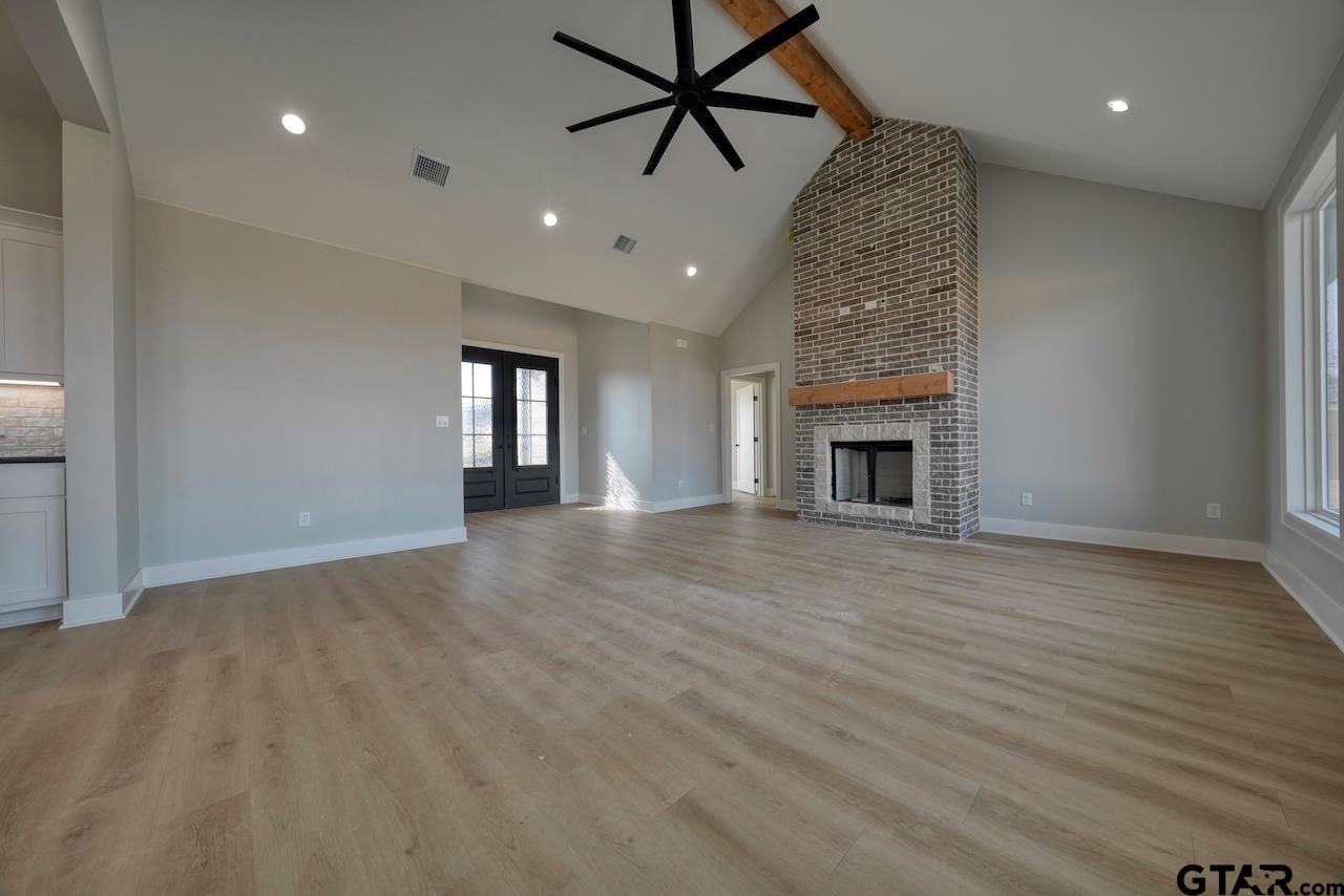 636 Prince Lane Tyler, TX 75704 - Photo 6 of 38 an empty room with wooden floor fireplace and windows