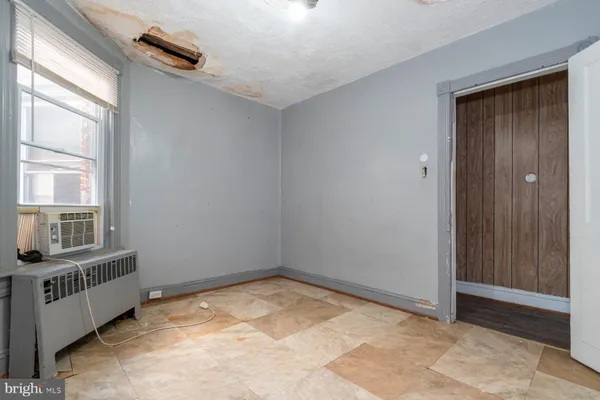 an empty room with chandelier fan and windows