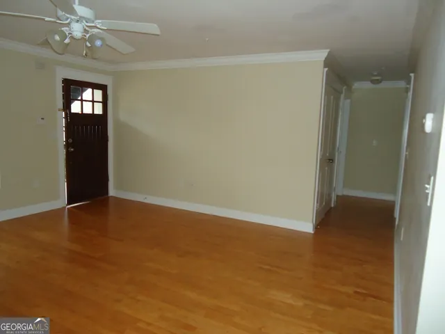 an empty room with wooden floor closet and windows
