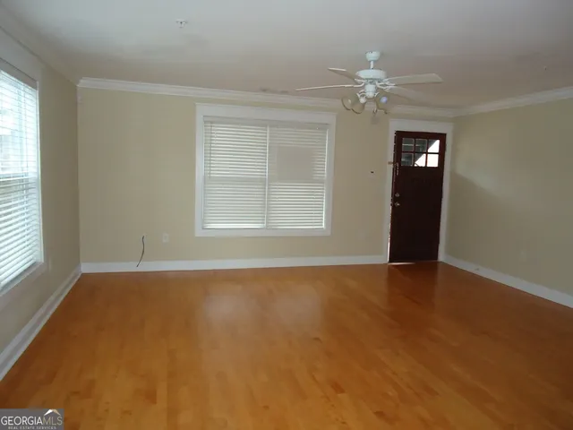 an empty room with chandelier fan and windows