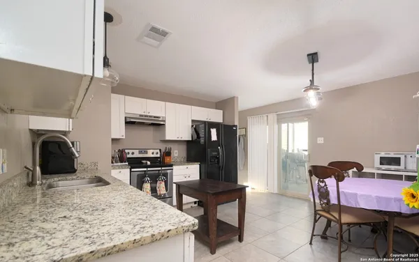 a kitchen with stainless steel appliances granite countertop a stove top oven a sink dishwasher and a refrigerator with wooden floor