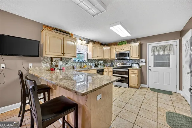 a kitchen with stainless steel appliances granite countertop a stove a sink a microwave a dining table and chairs