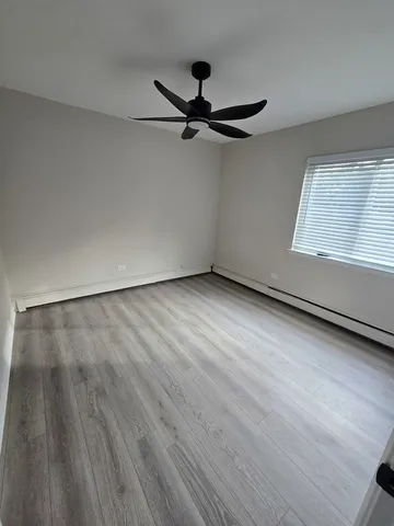 an empty room with wooden floor cabinet and windows
