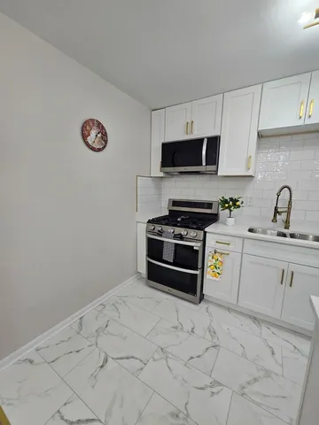 a kitchen with a sink a stove top oven and white cabinets