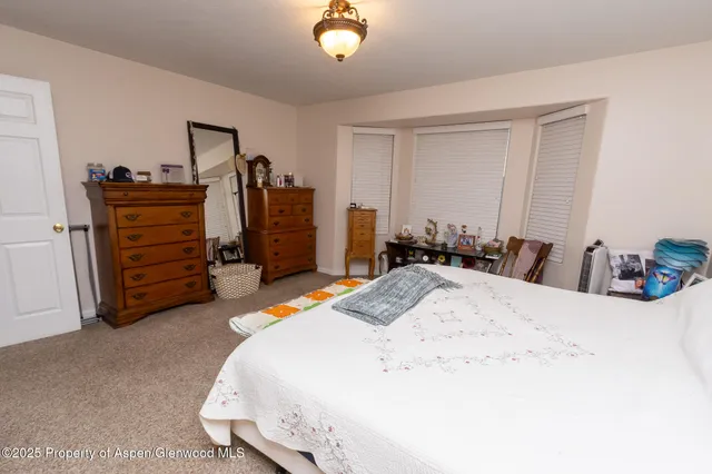 a bedroom with a bed chair and a lamp on a dresser