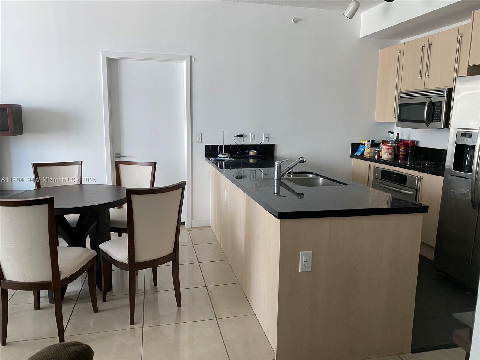 1111 Southwest 1st Avenue, Unit 2516N Miami, FL 33130 - Photo 8 of 31 a kitchen with granite countertop a table chairs stove and microwave