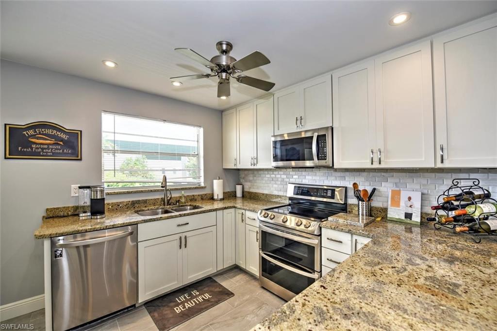 a kitchen with stainless steel appliances granite countertop a sink a stove a microwave a refrigerator and cabinets