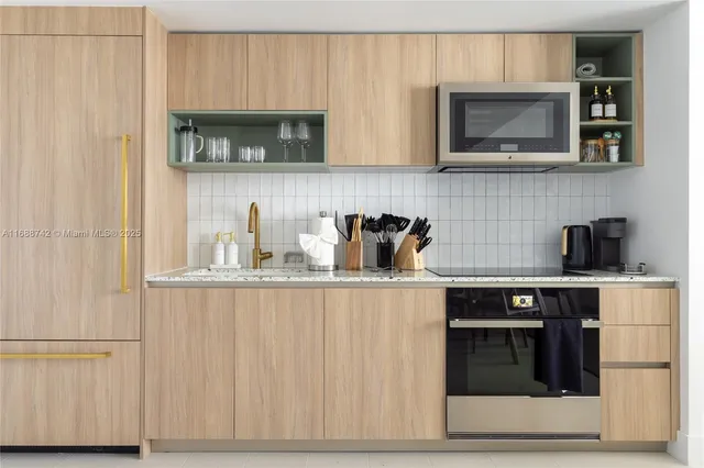 a kitchen with stainless steel appliances granite countertop white cabinets and a stove top oven