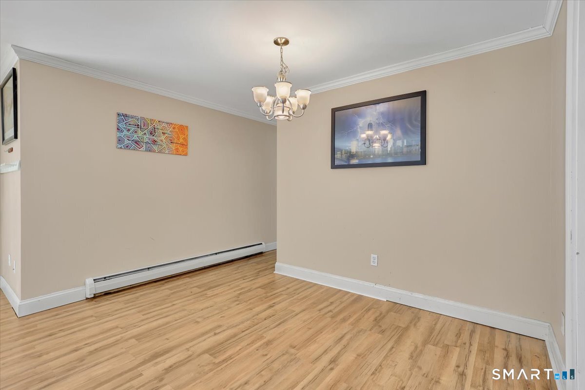 565 Talcottville Road, Unit 1A1 Vernon, CT 06066 - Photo 12 of 27 an empty room with wooden floor chandelier and hallway