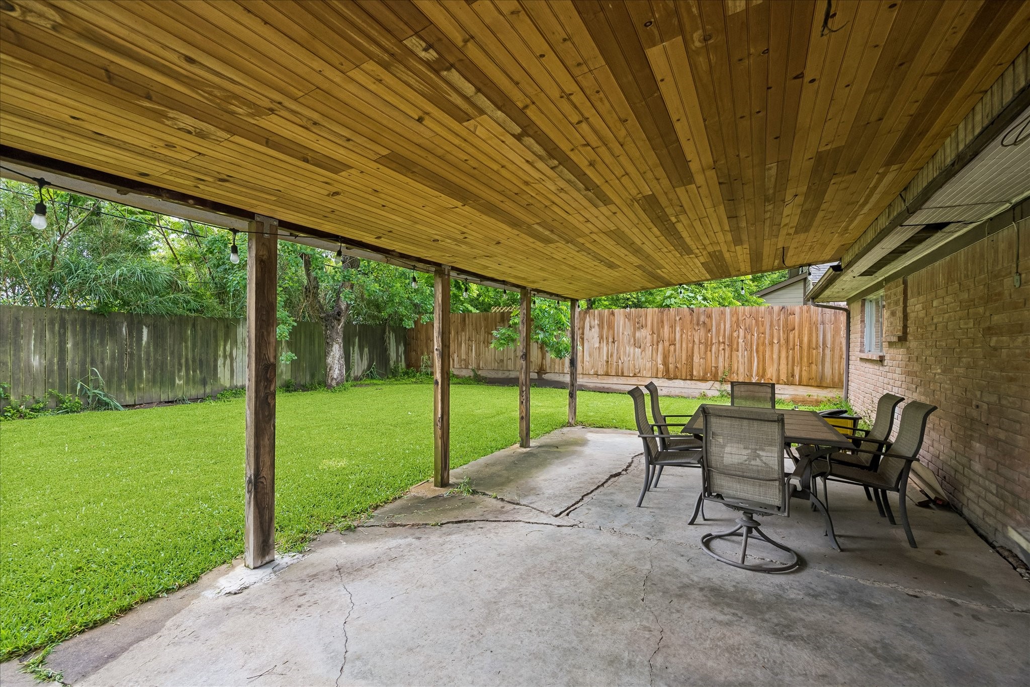 5526 Grape Street Houston, TX 77096 - Photo 5 of 10 a view of a backyard with table and chairs and couches with wooden fence and floor