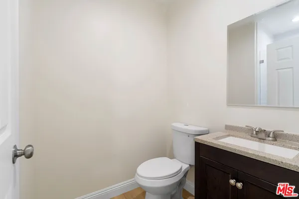 a bathroom with a granite countertop toilet sink and mirror