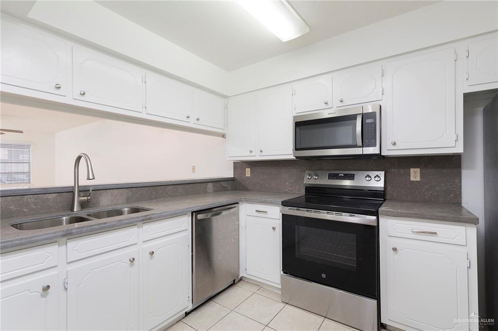 600 Toronto Avenue, Unit 14 McAllen, TX 78503 - Photo 4 of 14 Kitchen with stainless steel appliances, white cabinetry, light tile patterned floors, backsplash, and dark stone counters