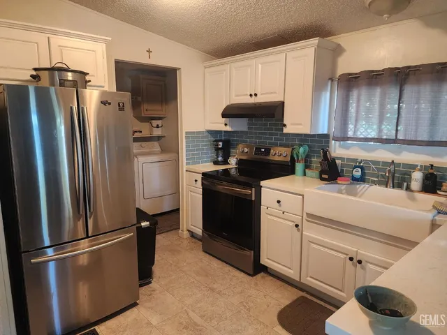 a kitchen with refrigerator a microwave a sink and cabinets