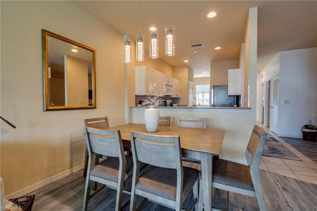 7930 Mahogany Run Lane, Unit 824 Naples, FL 34113 - Photo 17 of 40 a dining room with stainless steel appliances kitchen island granite countertop a dining table chairs and a refrigerator