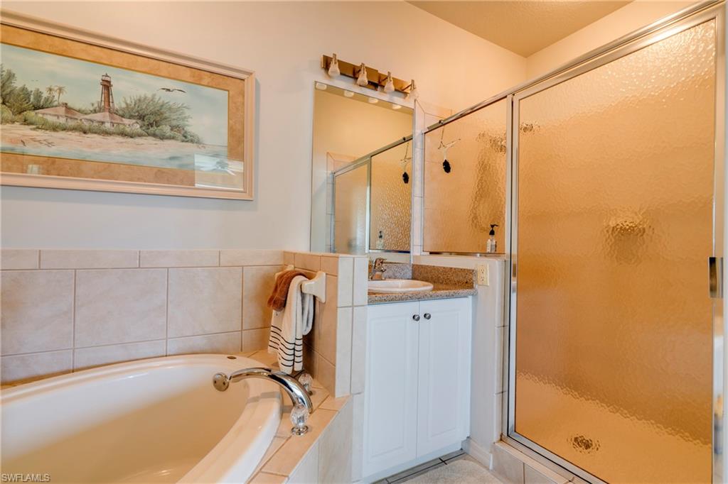 7930 Mahogany Run Lane, Unit 824 Naples, FL 34113 - Photo 24 of 40 a bathroom with a tub a sink and glass door