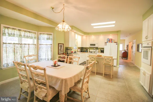 a dining room with furniture a chandelier and a large window