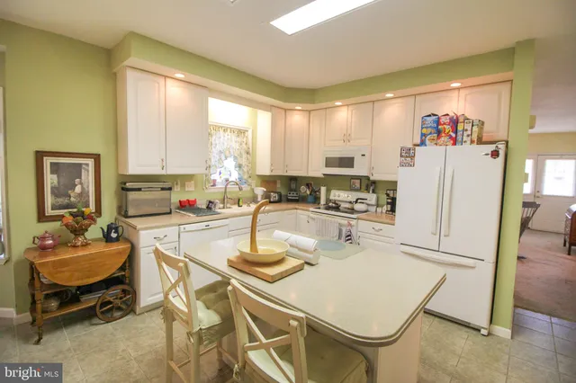 a kitchen with stainless steel appliances granite countertop a refrigerator a sink and white cabinets