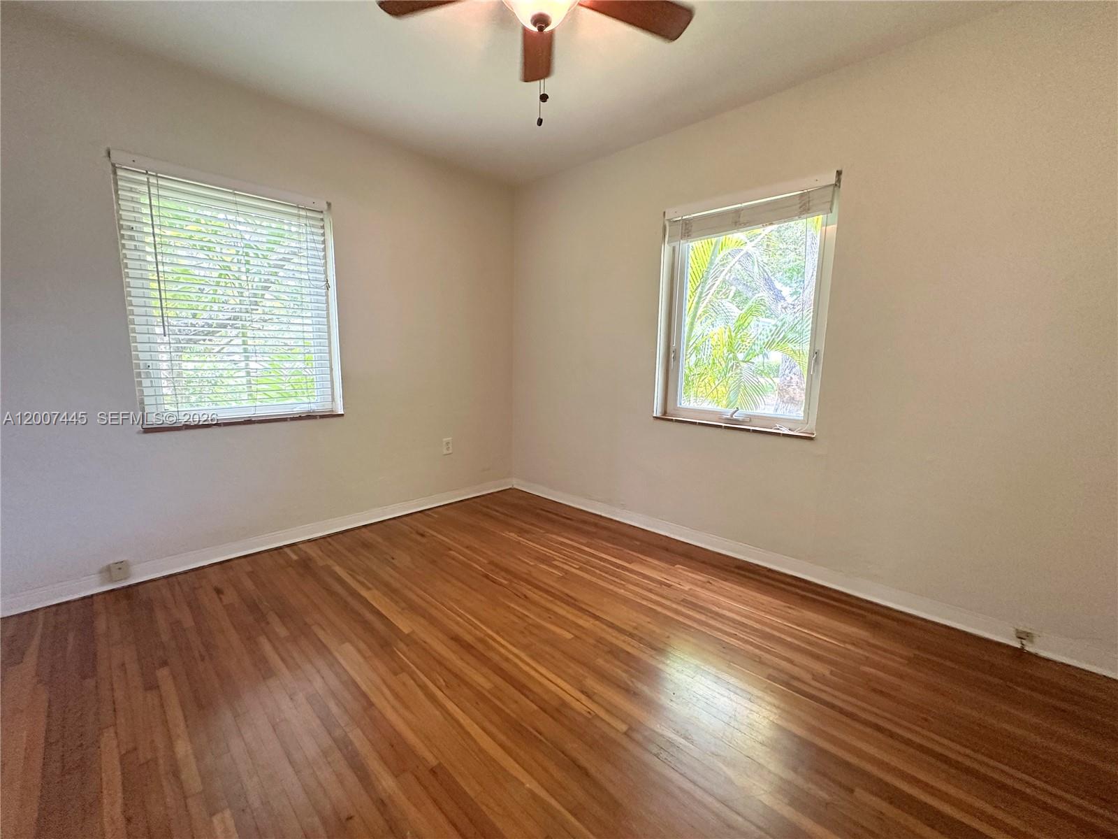 7734 Southwest 55th Avenue, Unit B Miami, FL 33143 - Photo 9 of 11 a view of an empty room with wooden floor and a window