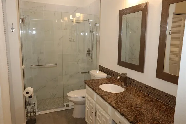 a bathroom with a granite countertop sink toilet and shower