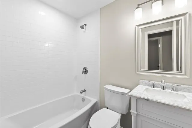 a bathroom with a granite countertop toilet a sink and a bathtub