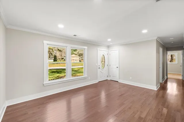 an empty room with wooden floor and windows