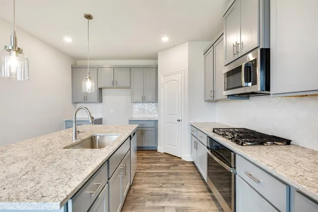 a kitchen with stainless steel appliances granite countertop a sink stove and microwave