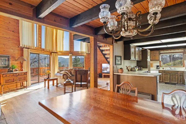 a dining room with wooden floor a chandelier a wooden table and chairs