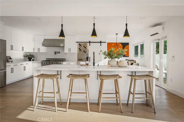 a kitchen with stainless steel appliances kitchen island granite countertop a dining table chairs and white cabinets