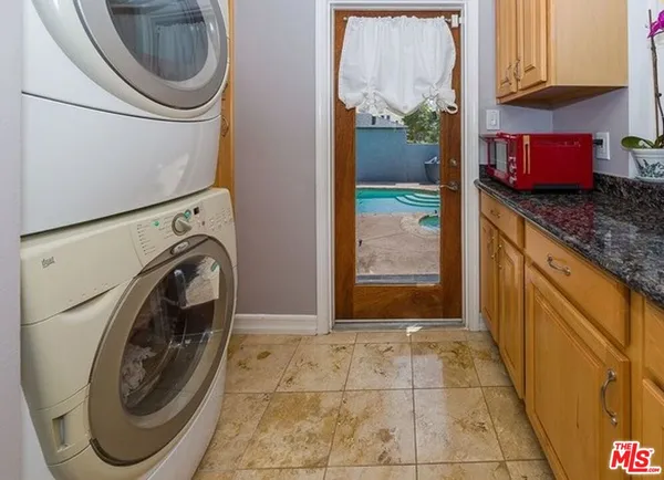 a bathroom with a granite countertop a sink a washer and dryer